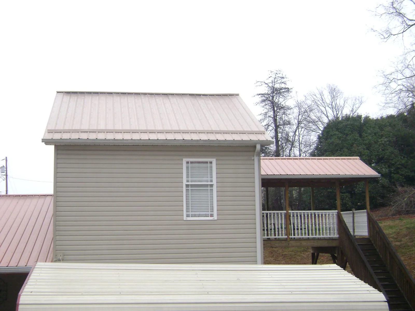 Tan metal roofs on a two story addition and attached porch, from a Roof Replacement job in Thornton